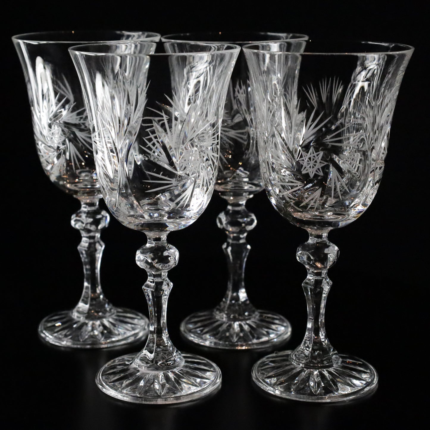 Four beautifully designed Antoinette white wine glasses, featuring ornate crystal cuts and a graceful silhouette, ideal for fine dining.