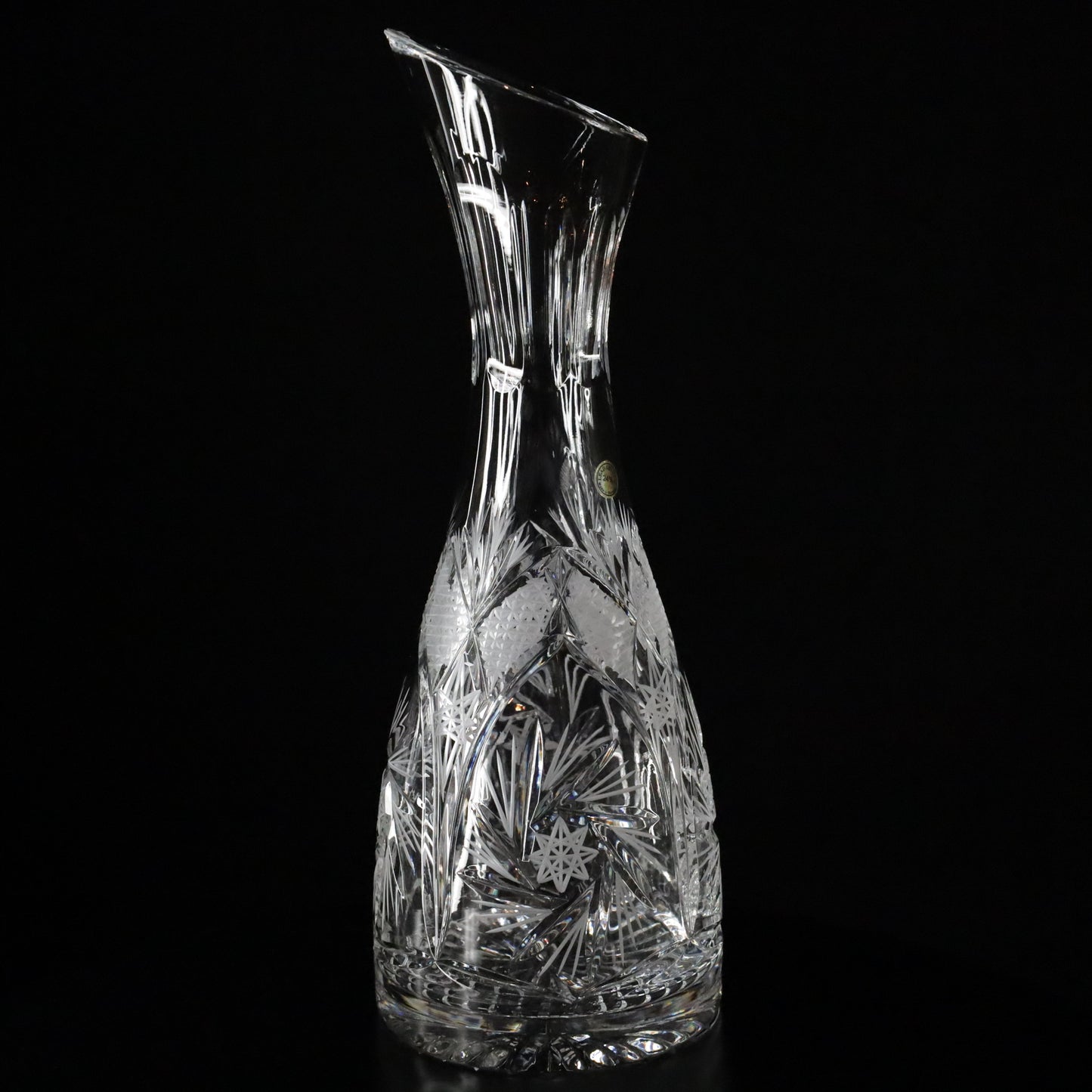 A refined Antoinette crystal wine decanter with a slender design and intricate etched patterns, displayed on a sleek black surface.