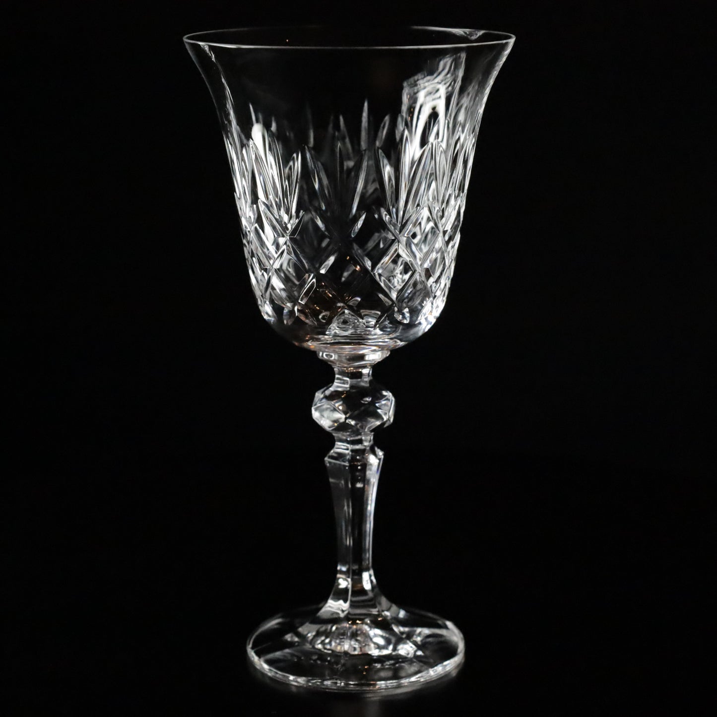 Elegant Crown crystal wine glasses featuring intricate diamond-cut patterns and slender stems, displayed gracefully on a sleek black surface.