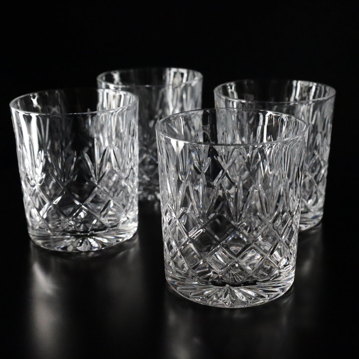 Refined Crown crystal tumblers with timeless diamond-cut patterns, beautifully displayed as a set of four for elegant gatherings.