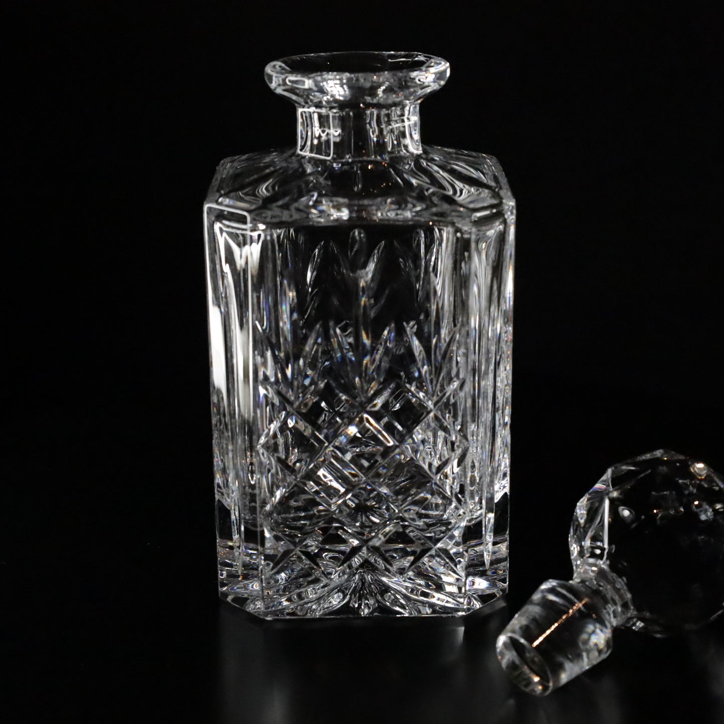 Sophisticated Crown whisky decanter with ornate cuts and a timeless design, radiating elegance against a dark backdrop.