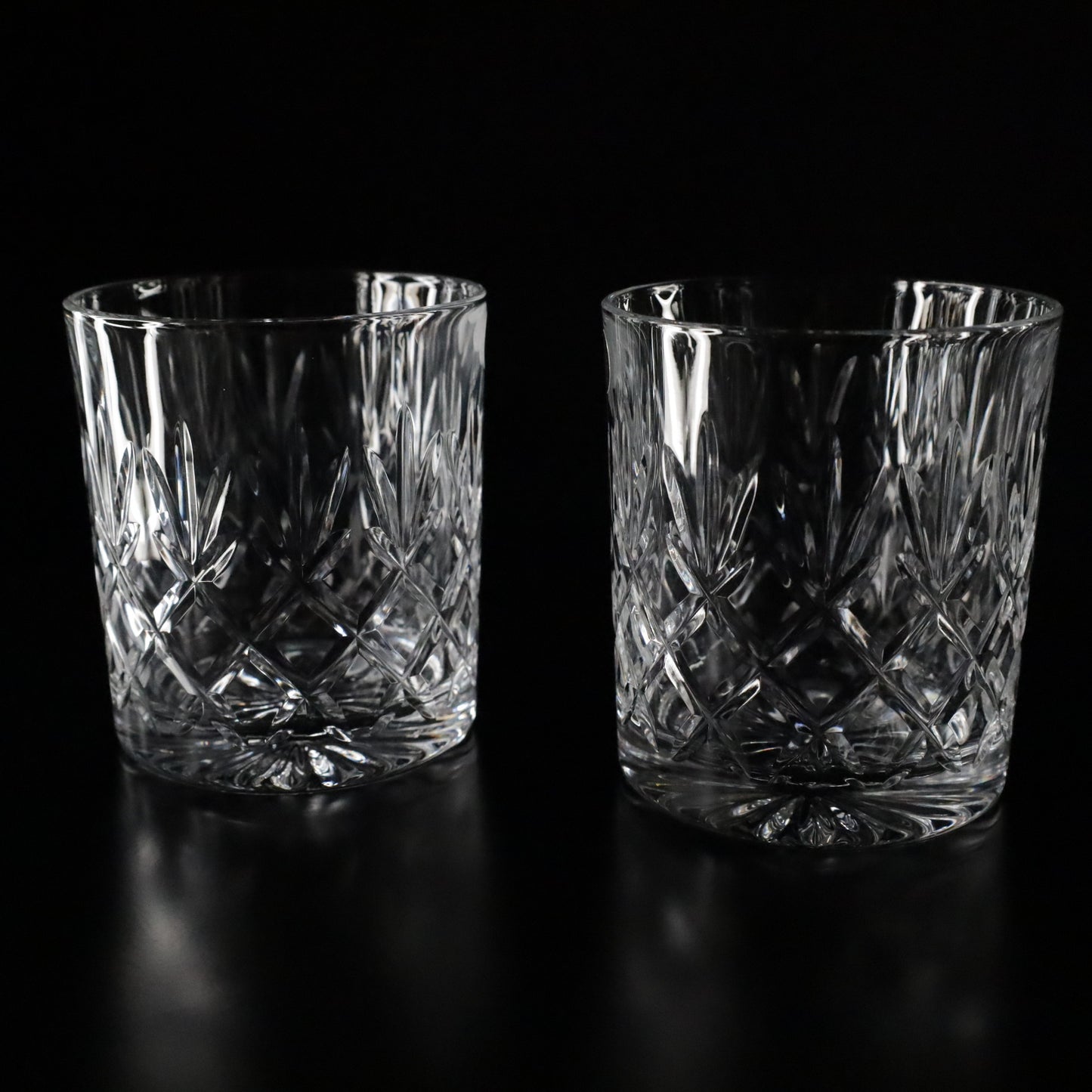 Luxurious Crown crystal tumblers with intricate diamond-cut patterns, offered as a sleek two-piece set for personal enjoyment.