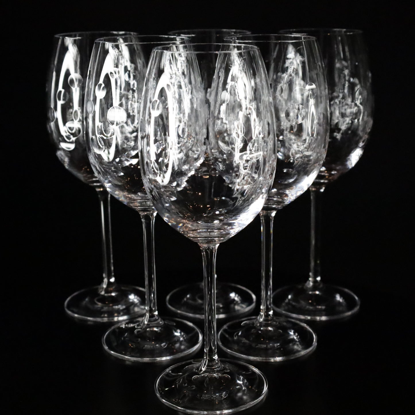 Elegant Nebula red wine glass featuring a unique etched bubble design and slender stem, displayed against a sleek black background.