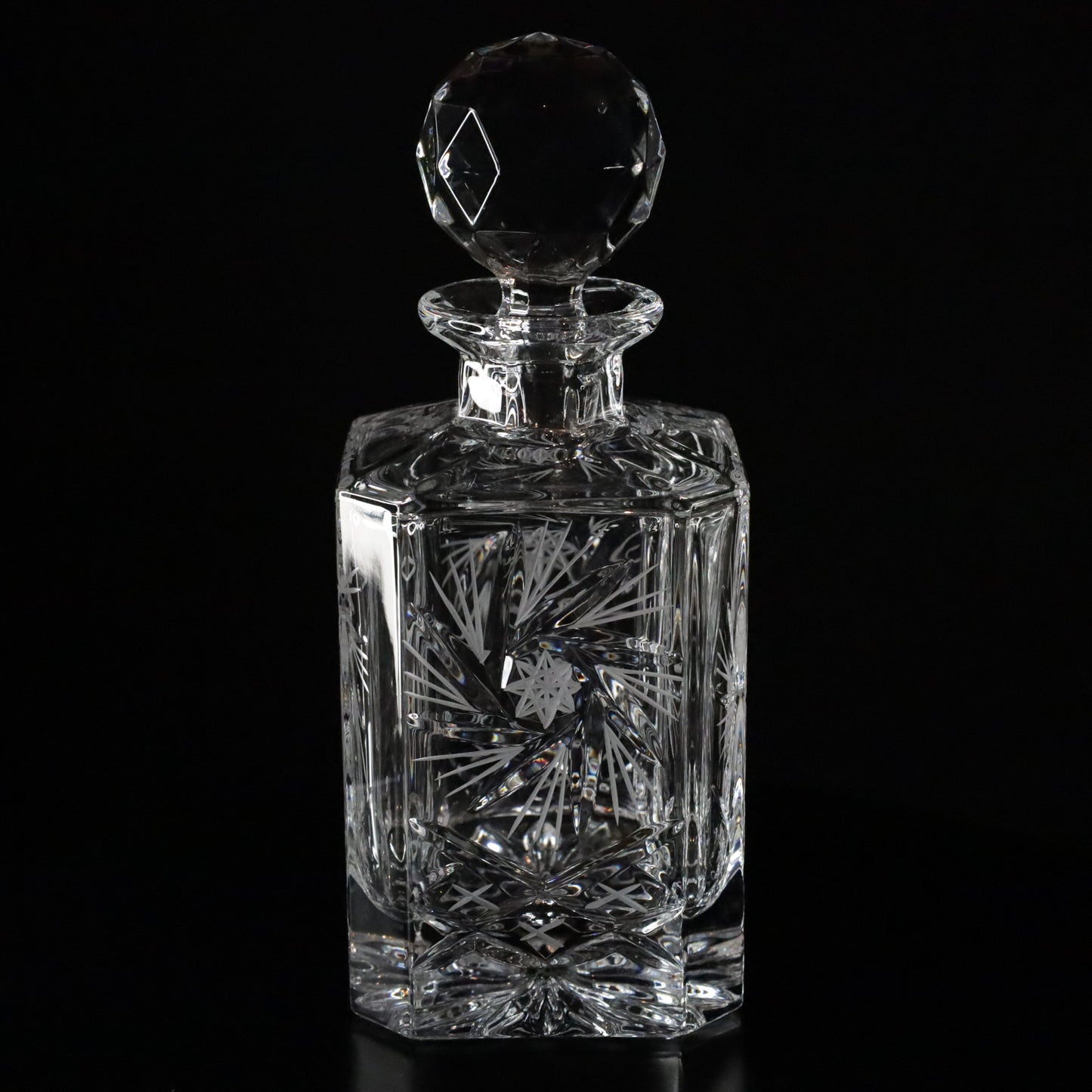 Luxurious Antoinette crystal whisky decanter featuring detailed etching and a finely crafted faceted stopper, set against a dark background.
