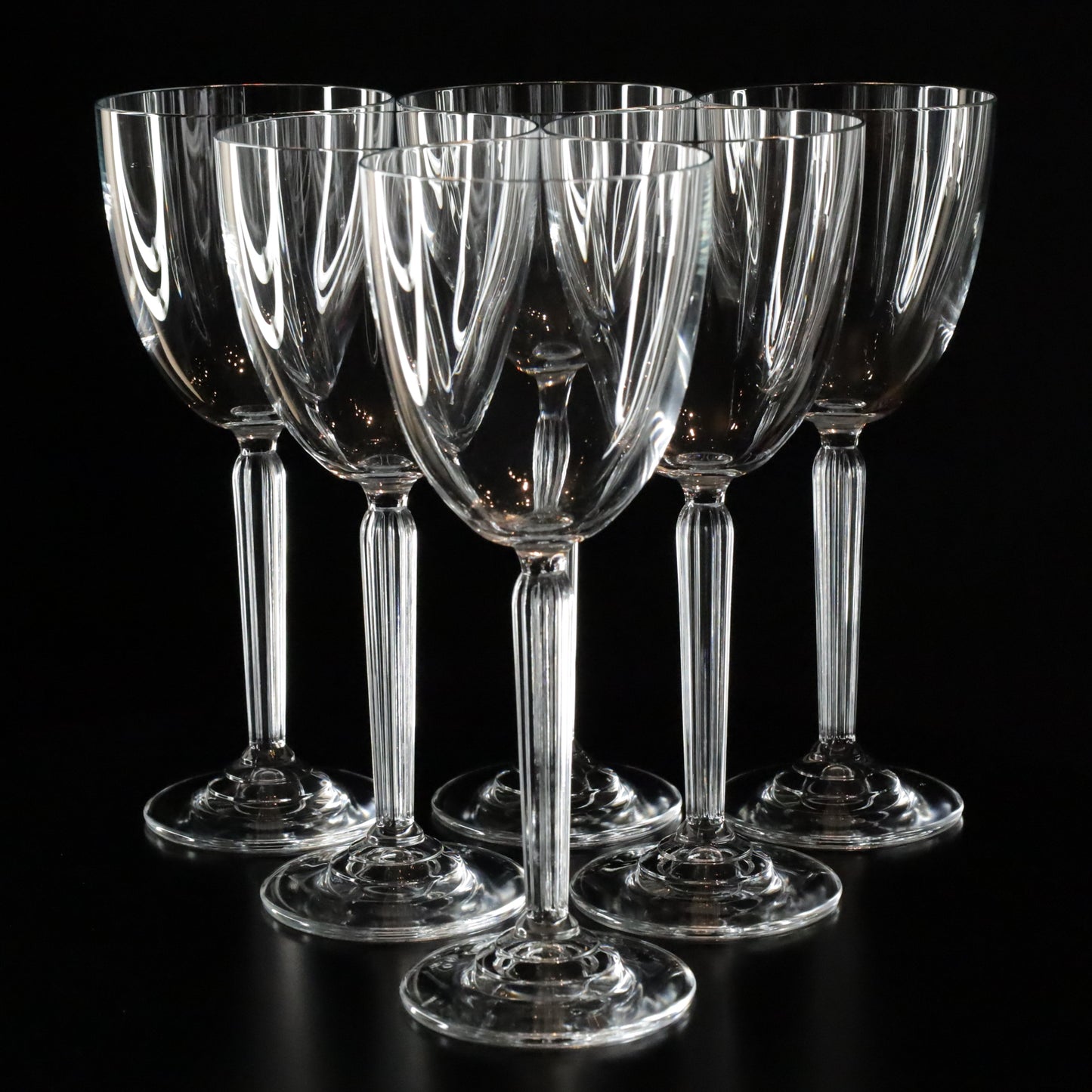 Elegant Aurora white wine glasses with a refined, minimalist design, displayed in a set of six on a sleek black surface.