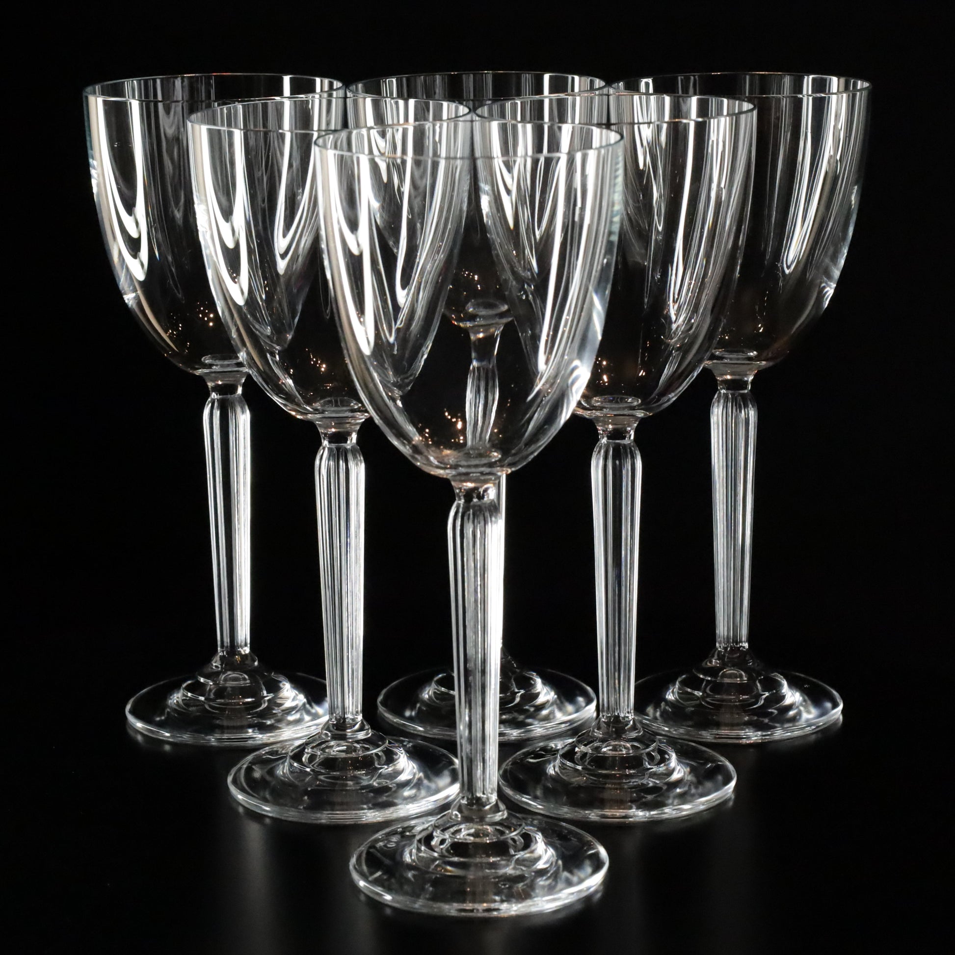 Elegant Aurora white wine glasses with a refined, minimalist design, displayed in a set of six on a sleek black surface.