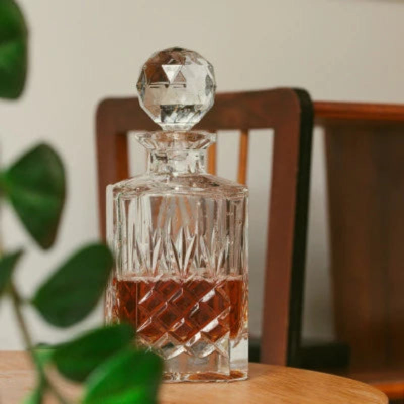 A Crown Whiskey Decanter made of premium crystal, featuring intricate etching and a faceted stopper, perfect for storing and serving whiskey or spirits.