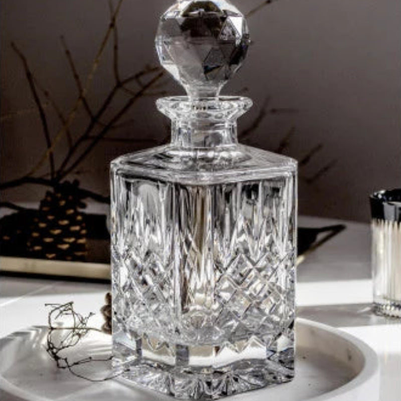 A Crown Whiskey Decanter made of premium crystal, featuring intricate etching and a faceted stopper, perfect for storing and serving whiskey or spirits.