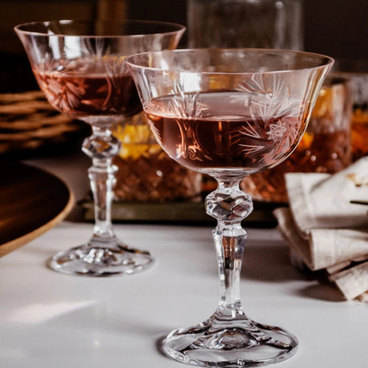 An elegant champagne flute with a long, slender stem, crystal-clear bowl, and a golden rim, filled with sparkling champagne, placed on a luxurious black and gold tabletop setting.